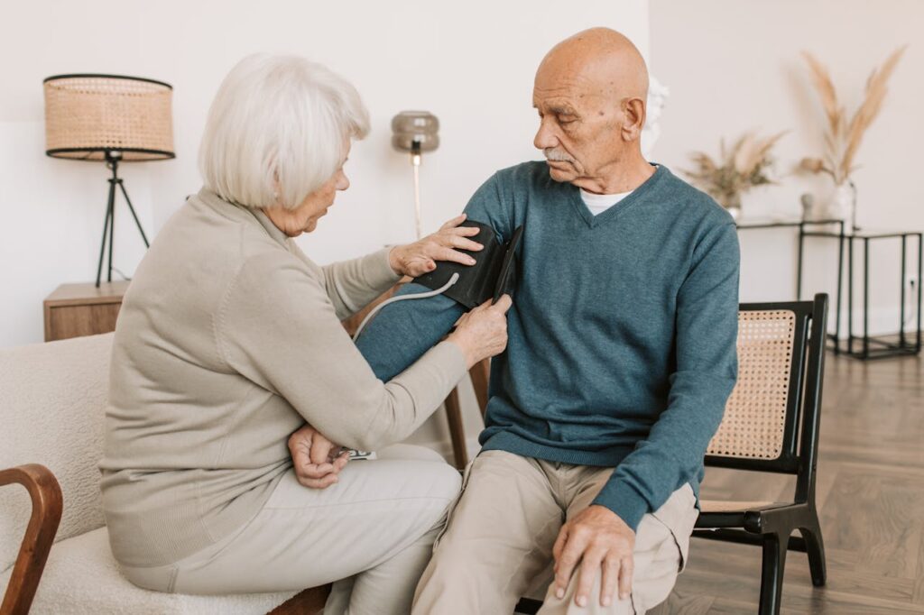 Elderly couple involved in a home blood pressure checkup, emphasizing health and care.